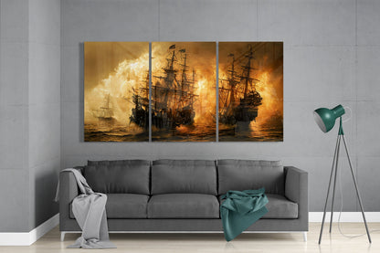 Three-panel golden glass art depicting dramatic naval battle with flaming ships displayed above gray sofa in modern living room.