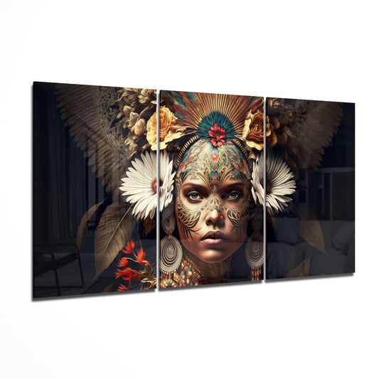 Three-panel glass wall art displaying an ornately decorated woman's face with facial tattoos, feathered headdress, and floral elements in warm earth tones and jewel colors.