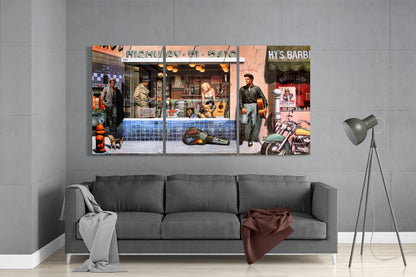 Multi-panel glass wall art depicting colorful vintage street scenes with storefronts, figures, and signage including "Highway 51" and "Hy's Barbi," hung above gray sofa.