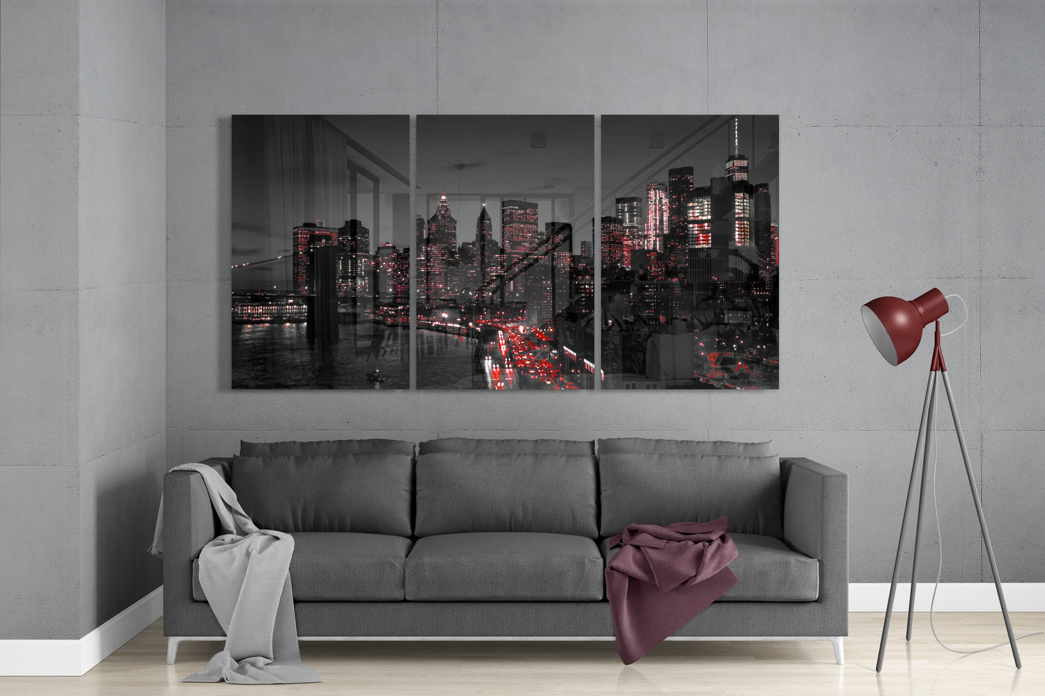 Three-panel glass wall art displaying a nighttime cityscape with illuminated skyscrapers and red traffic lights, hung above a gray sofa in a modern living room.