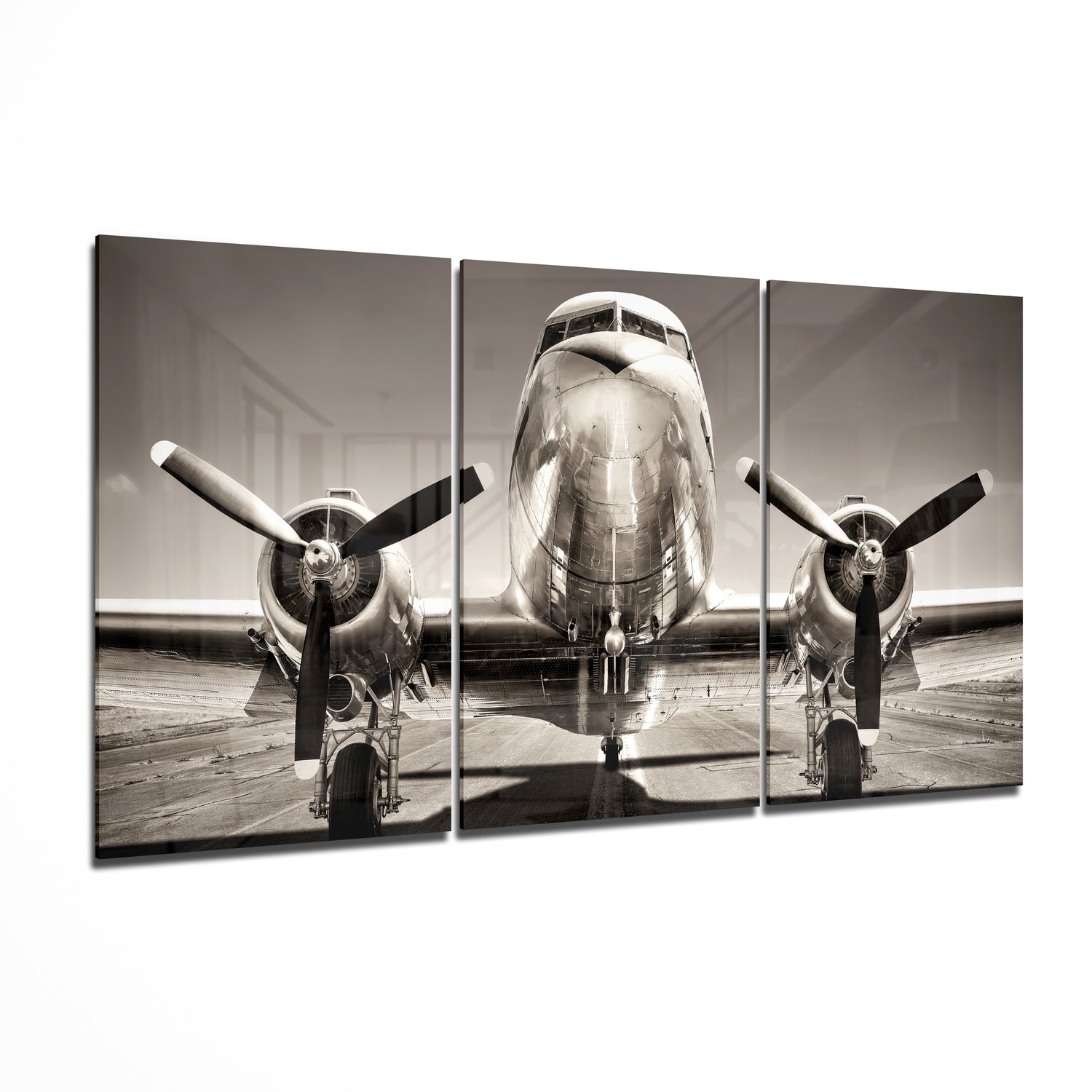 Front view of a vintage twin-engine aircraft on a tarmac in sepia-toned black and white, displayed as a three-panel glass wall art piece.