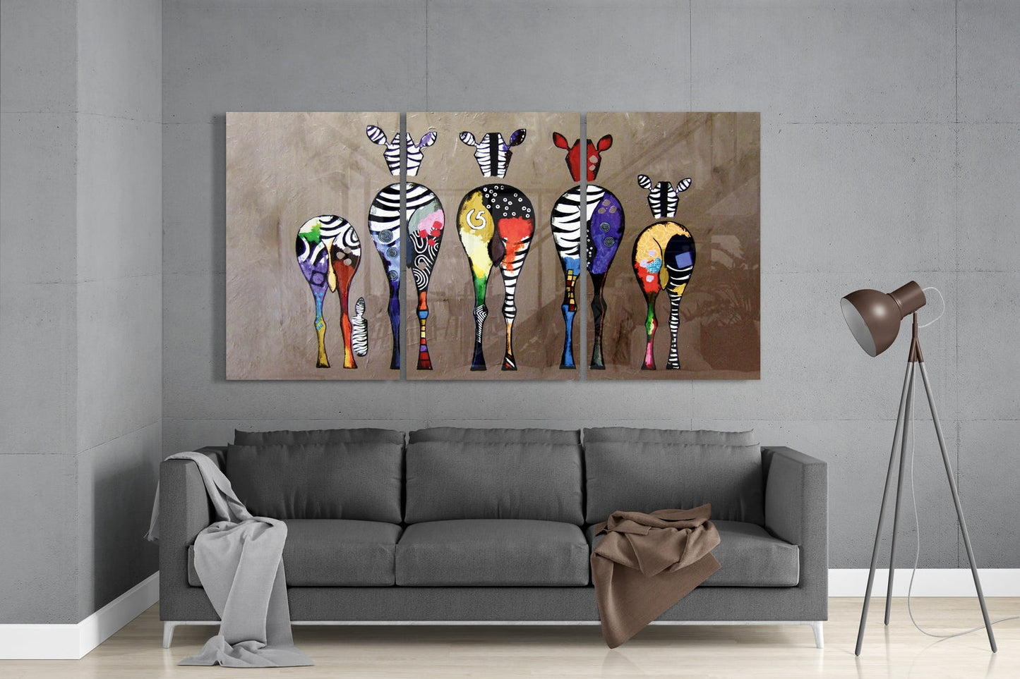 Colorful glass wall art featuring six zebras with patterned bodies displayed above gray sofa in modern living room.
