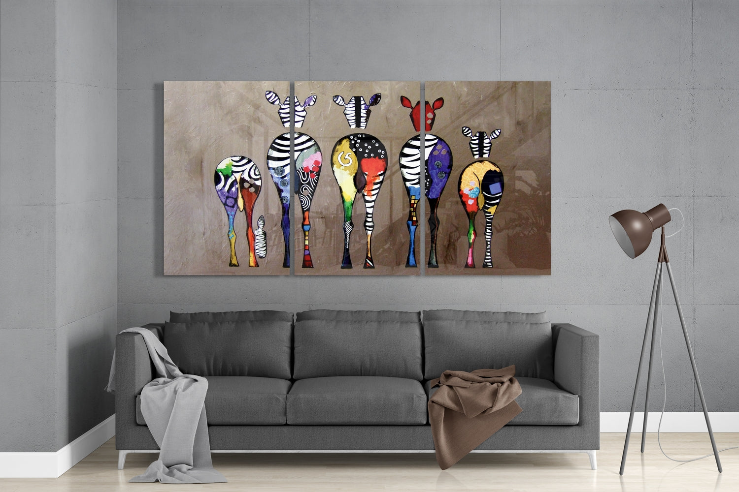 Colorful glass wall art featuring six zebras with patterned bodies displayed above gray sofa in modern living room.