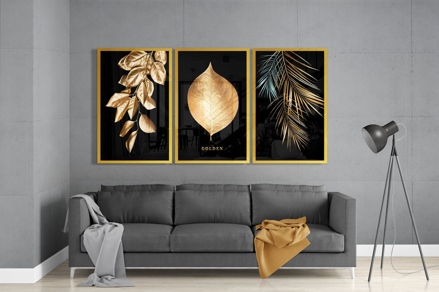 Three framed golden leaf prints on black backgrounds displayed above gray sofa in modern living room setting.