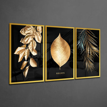 Three-panel gold-framed glass wall art displaying golden botanical leaves and "GOLDEN" text on black background.
