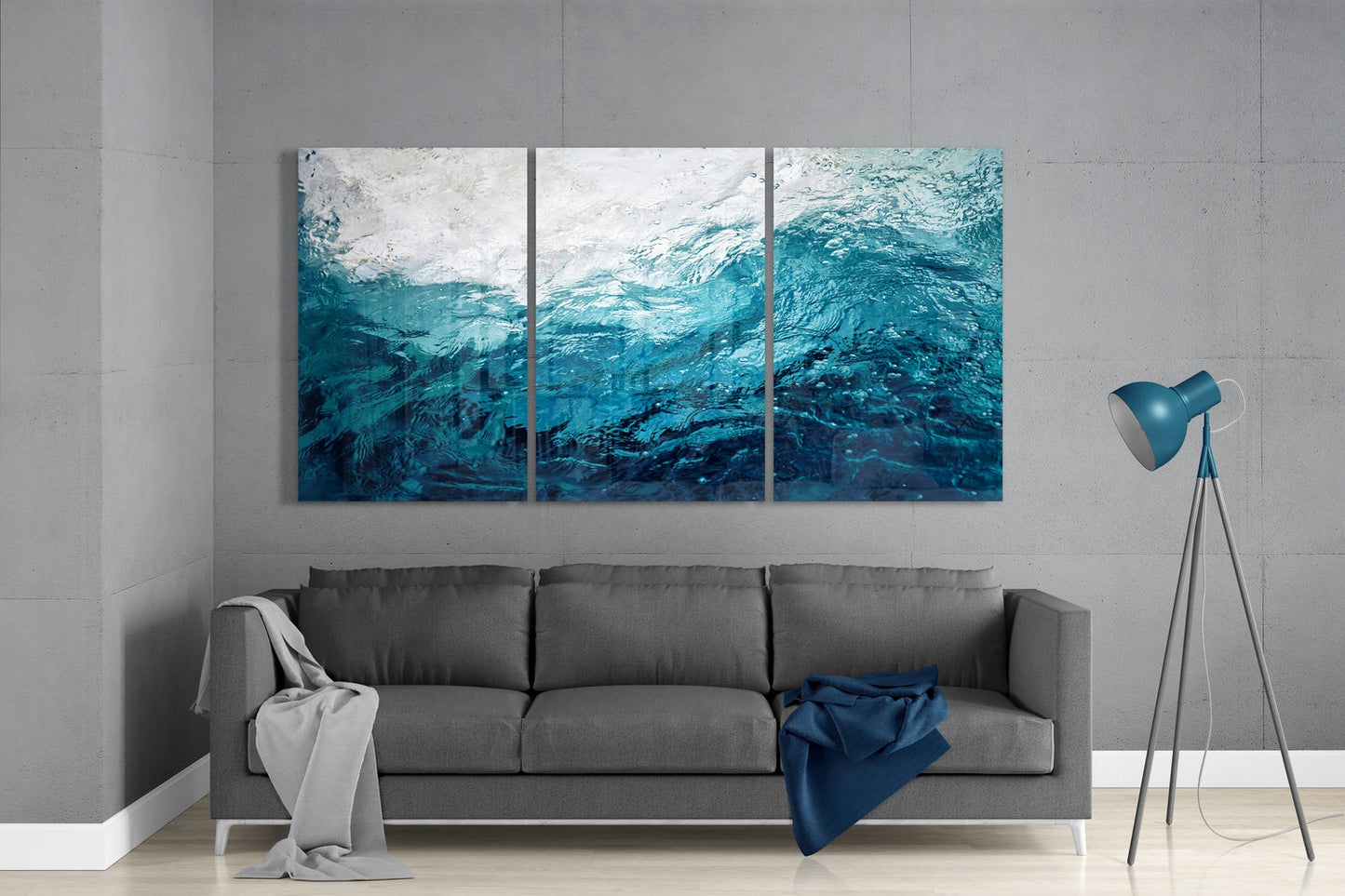 Three-panel teal and white water texture glass art hung above gray sofa in minimalist living room interior.