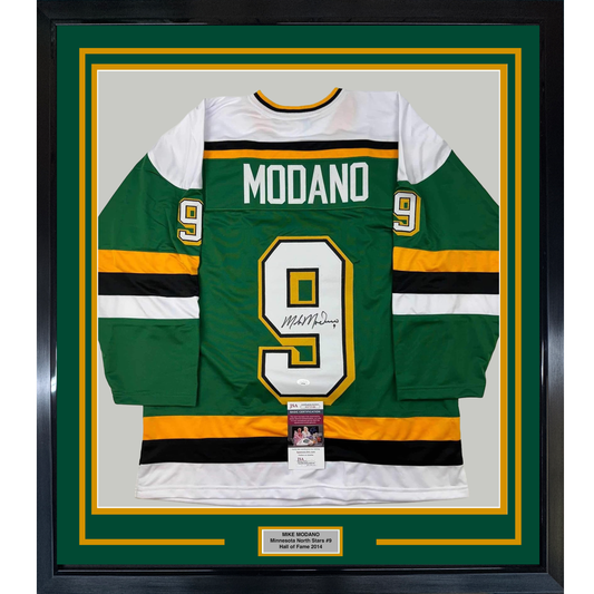 Framed green Minnesota North Stars hockey jersey number 9 with "MODANO" nameplate, signed, featuring gold and black horizontal stripes and JSA certification sticker.