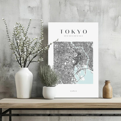 White ceramic vase with greenery on wooden base and Modern Tokyo Map print