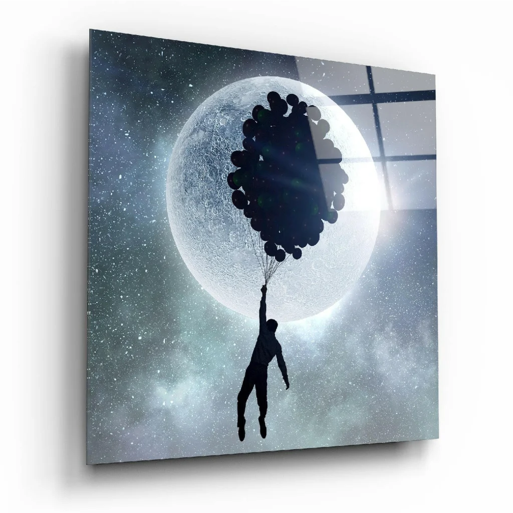 Black silhouette holding balloons against moon in glass wall art