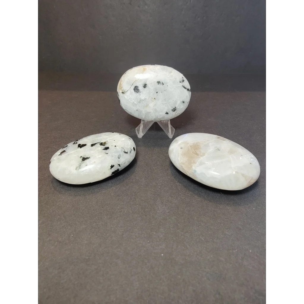 Three smooth oval-shaped white moonstone polished stones with black and beige speckles for heart and palm use
