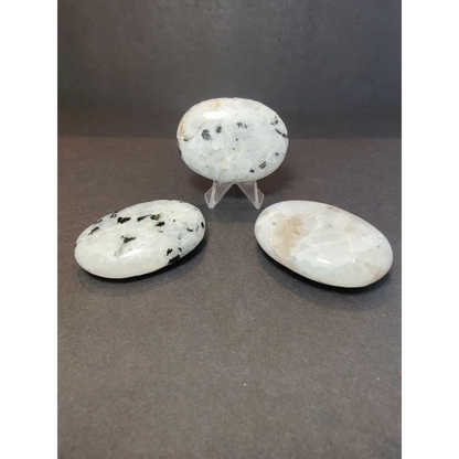 Three smooth oval-shaped white moonstone polished stones with black and beige speckles for heart and palm use
