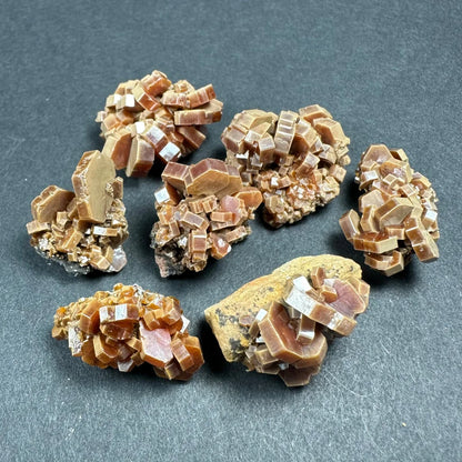 Brown translucent cubic crystal thumbnails on rock bases in acrylic box