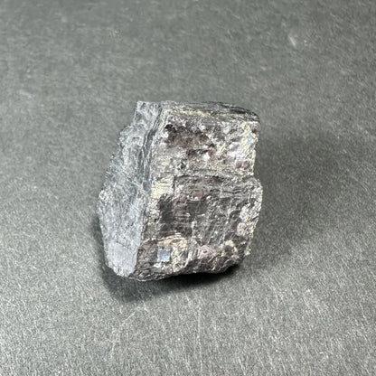 Rough silvery-gray Moroccan mineral thumbnail specimen in acrylic box