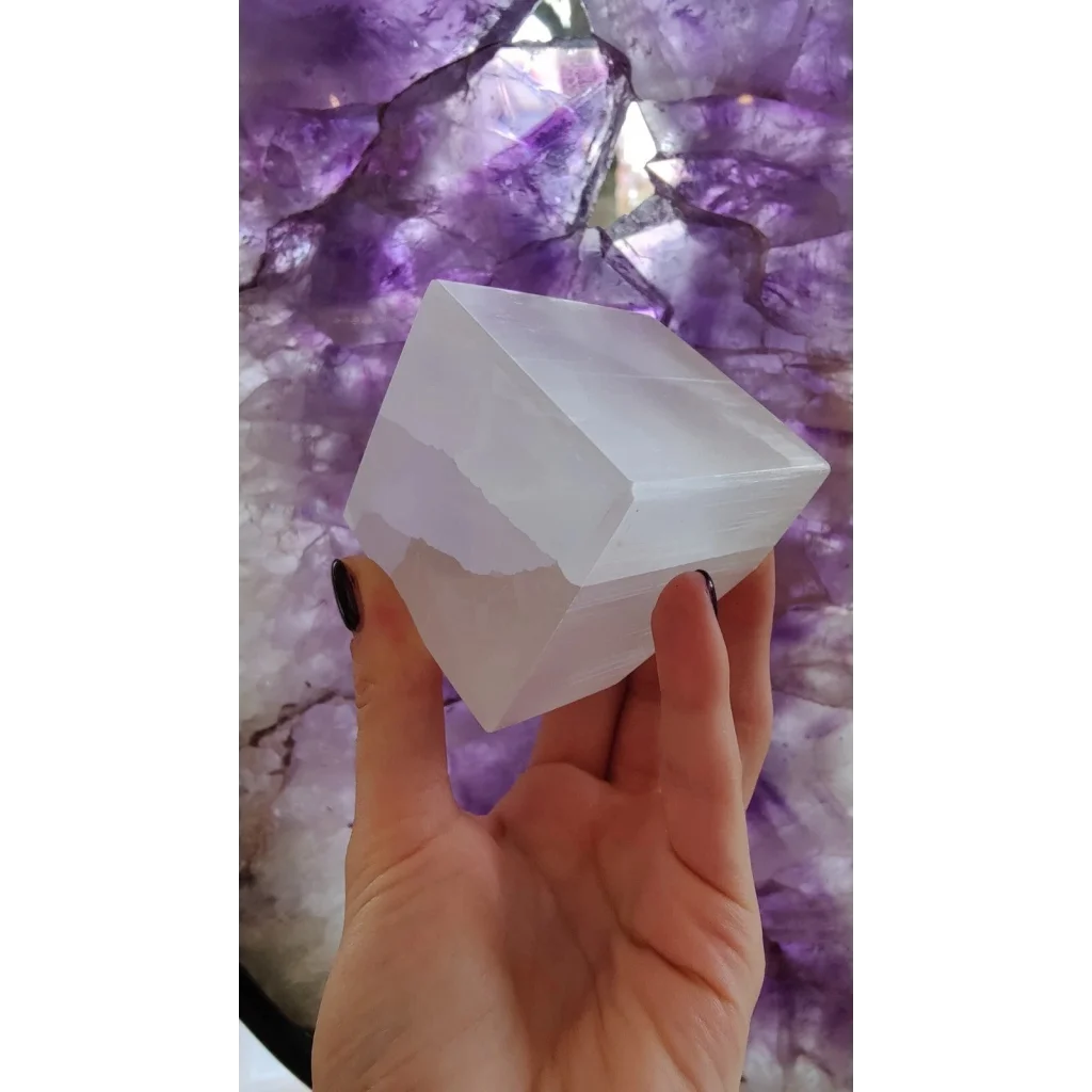 Hand holding translucent Moroccan selenite crystal cube with natural striations