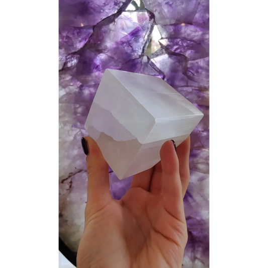 Hand holding translucent Moroccan selenite crystal cube with natural striations