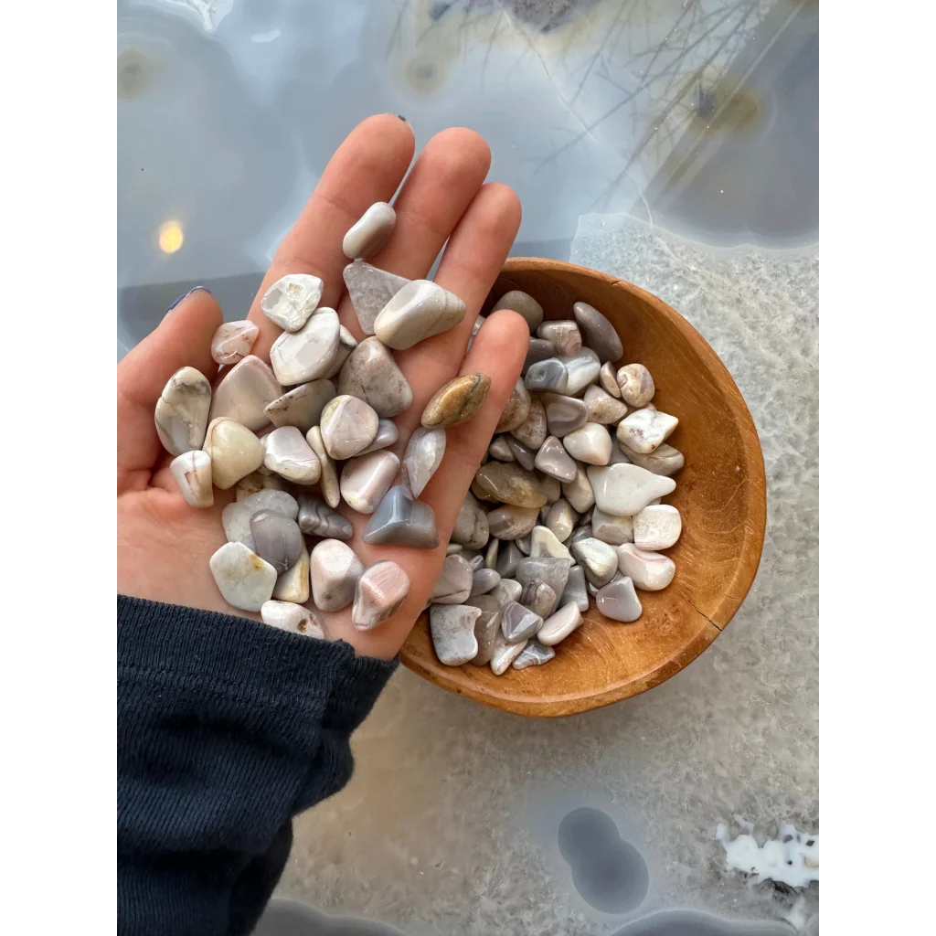 Hand holding natural agate tumbled stone collection in earthy tones