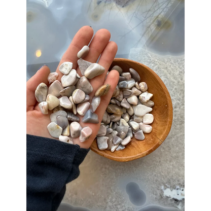 Hand holding natural agate tumbled stone collection in earthy tones