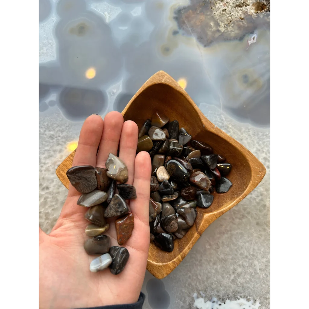 Hand holding natural agate tumbled stone collection in earthy brown tones
