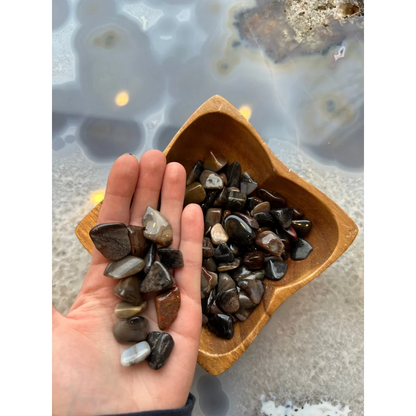 Hand holding natural agate tumbled stone collection in earthy brown tones