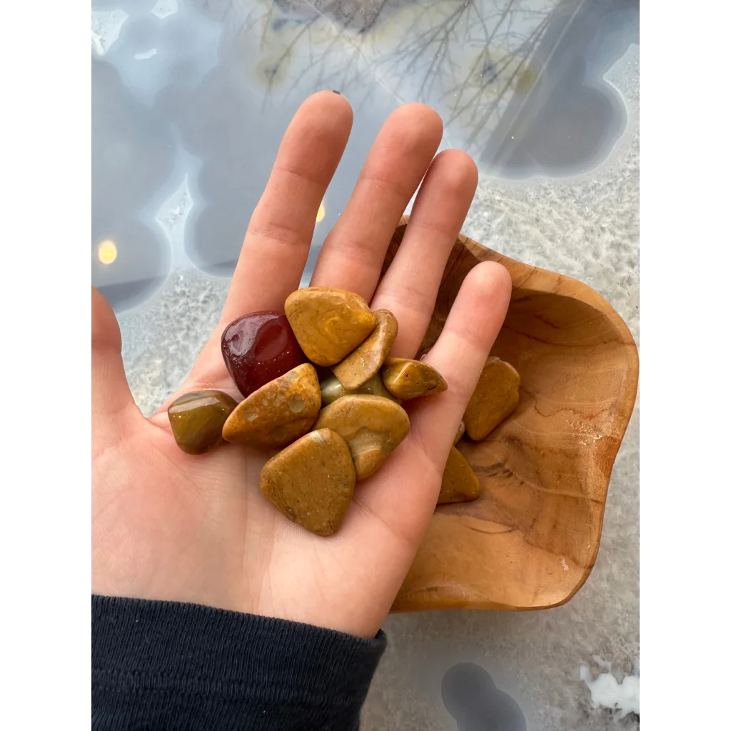 Hand holding natural agate tumbled stone collection in earthy tones