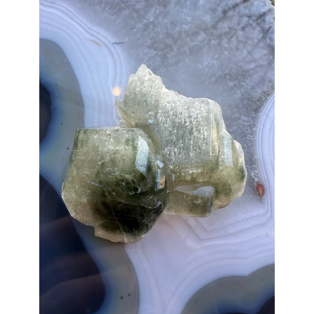 Natural green fluorapatite cluster on swirling agate slab