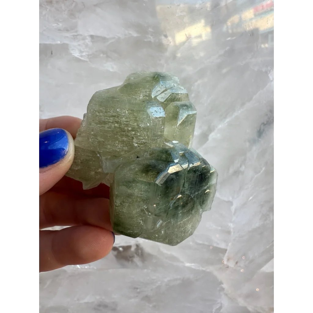Hand holding translucent green fluorapatite cluster crystal specimen