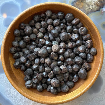 Wooden bowl of natural red almandine garnet stones from China