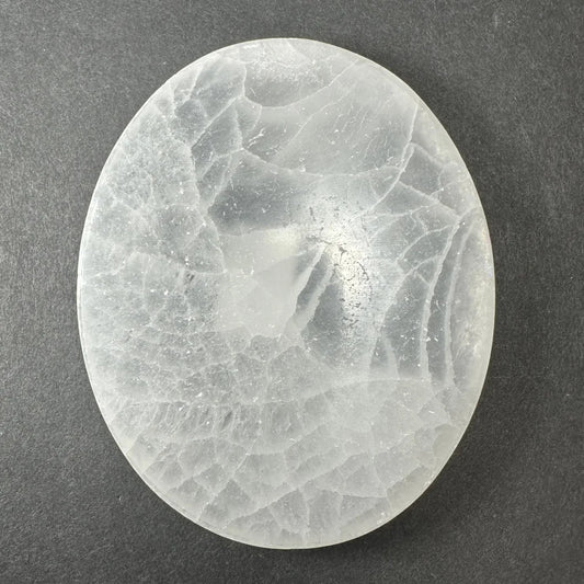 Translucent oval selenite slice with crystalline fractures and reflections