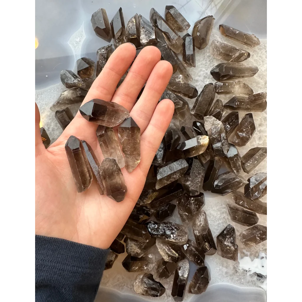 Hand holding natural smoky quartz point crystals in brown shades