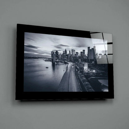 Black-framed glass wall art of monochrome cityscape with lit skyscrapers and river