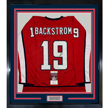 Red Washington Capitals hockey jersey number 19 with "BACKSTROM" nameplate, signed, displayed in framed matting with JSA certification label visible.