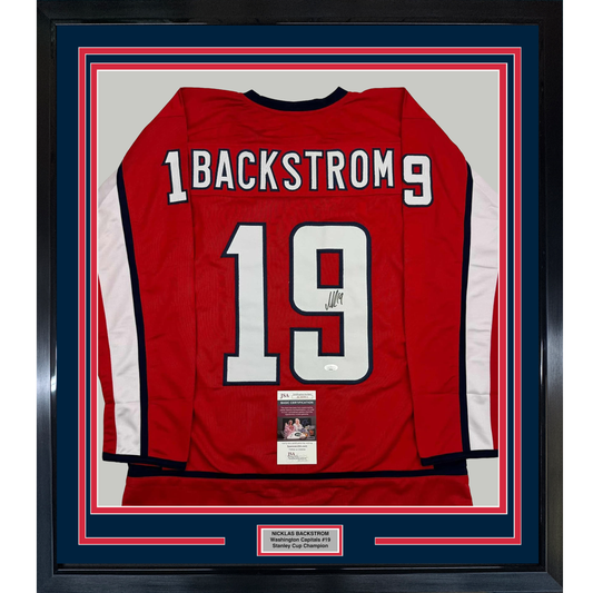 Red Washington Capitals hockey jersey number 19 with "BACKSTROM" nameplate, signed, displayed in framed matting with JSA certification label visible.