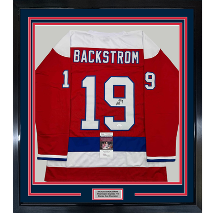 Framed red Washington Capitals hockey jersey number 19 with Backstrom nameplate, signed, displayed front-facing with authenticity certificates.
