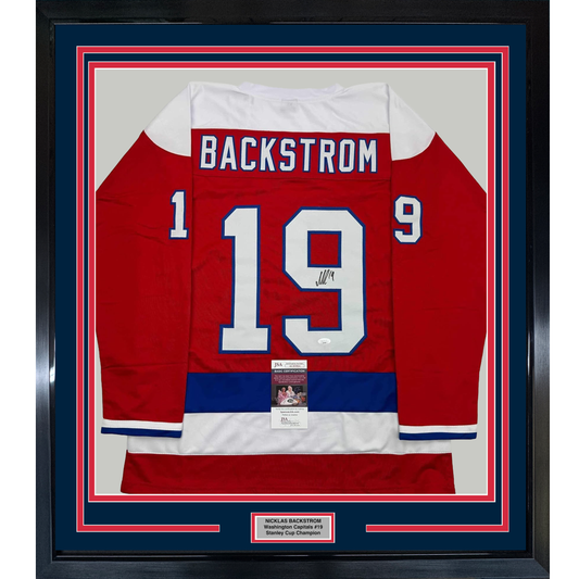 Framed red Washington Capitals hockey jersey number 19 with Backstrom nameplate, signed, displayed front-facing with authenticity certificates.