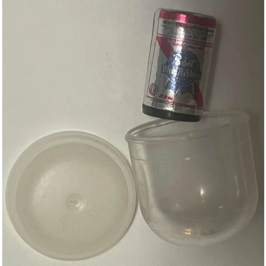 Bottle of vodka balanced on a cup next to Pabst Blue Ribbon lid from the 70s