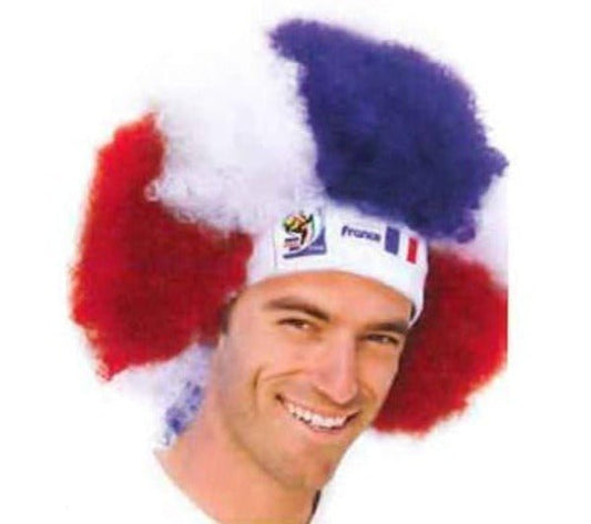 Man wearing red, white, and blue afro wig with France headband and 2006 FIFA World Cup logo, smiling at camera.