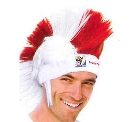 Man wearing white and red mohawk wig with FIFA World Cup logo, smiling at camera against white background.