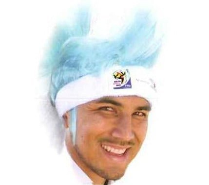 Man wearing light blue mohawk wig with white headband featuring purple emblem, smiling at camera against white background.