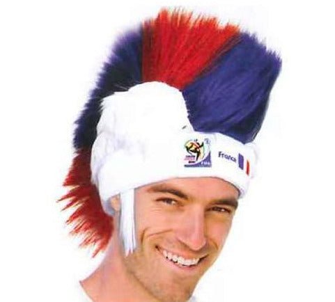 Man wearing red, white, and blue mohawk wig with France FIFA World Cup badge on white headband, smiling at camera.