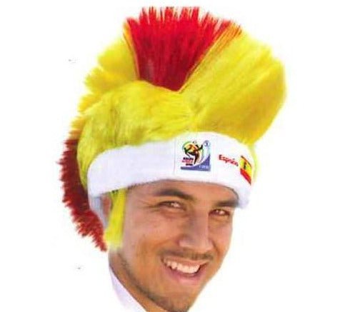 Man wearing yellow and red mohawk wig with white headband displaying FIFA World Cup logo, smiling at camera.