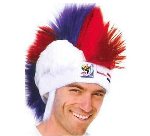 Man wearing white, red, and blue mohawk wig with FIFA World Cup logo, smiling at camera in front view.