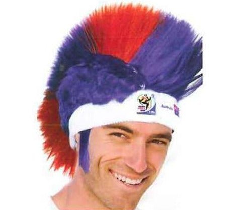 Man wearing blue and red mohawk wig with white headband featuring FIFA World Cup logo, smiling at camera.