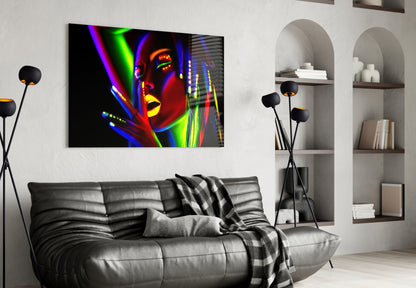 Colorful neon-lit female portrait glass art displayed above black leather sofa in modern living room.