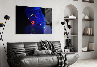 Modern living room with black leather sofa displaying vibrant neon-lit woman portrait glass art on white wall.