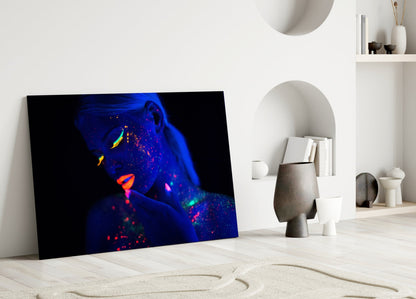 Neon portrait glass art leaning against white wall in minimalist interior with decorative objects.