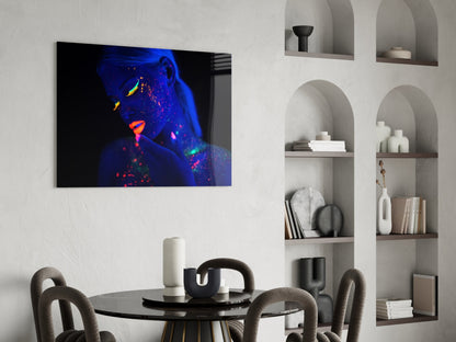 Glass wall art featuring neon-lit woman's portrait with blue, purple, and orange fluorescent colors displayed in modern dining room interior.
