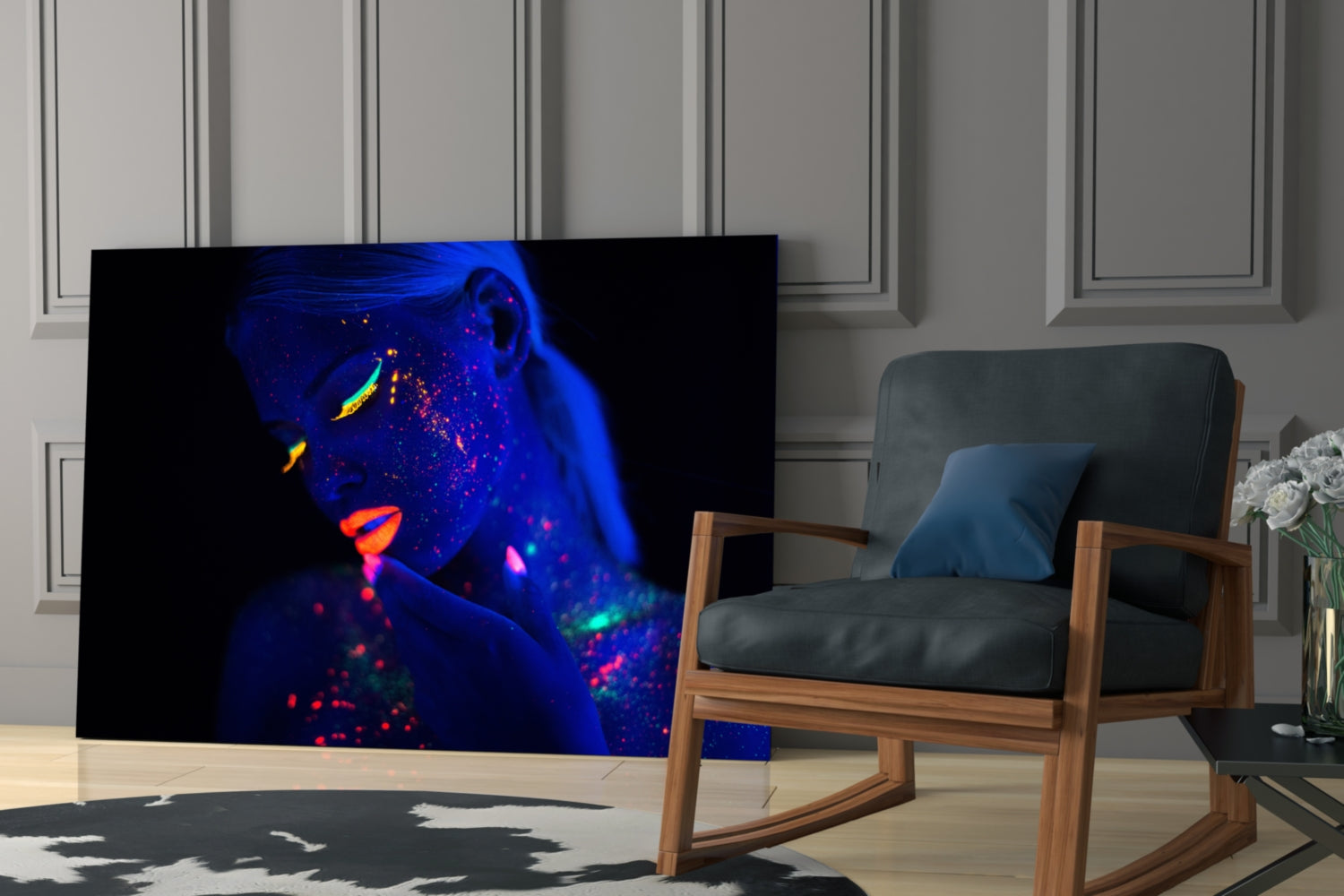 Neon portrait glass art displaying fluorescent blue, pink, and yellow face paint on a woman's face, displayed on a living room wall beside a wooden chair.