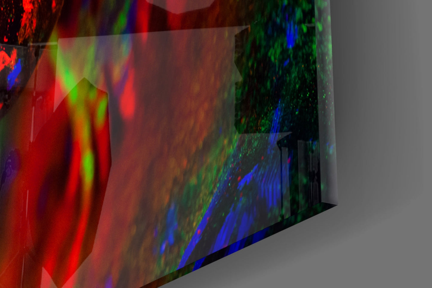 Close-up angled view of translucent glass wall art with multicolored light projections in red, green, and blue.