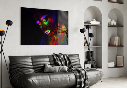 Colorful neon portrait of a woman's face displayed as glass wall art above a gray leather sofa in a modern living room.