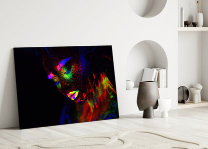 Colorful neon portrait of a woman's face displayed as glass art leaning against white interior wall with shelving.